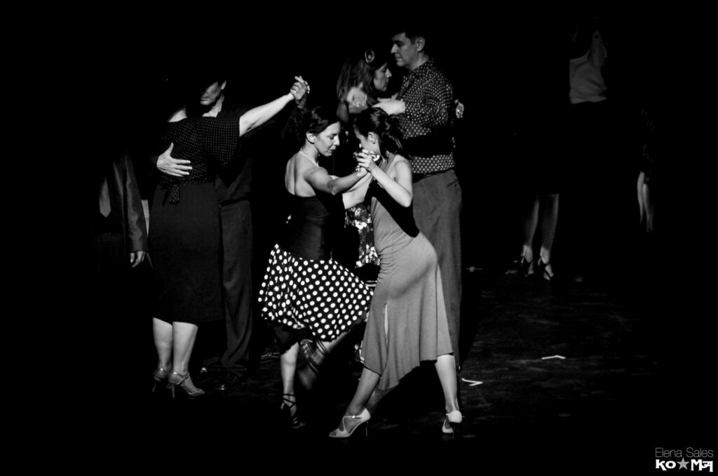 Stage tango exhibition with several couples on a stage, in black and white